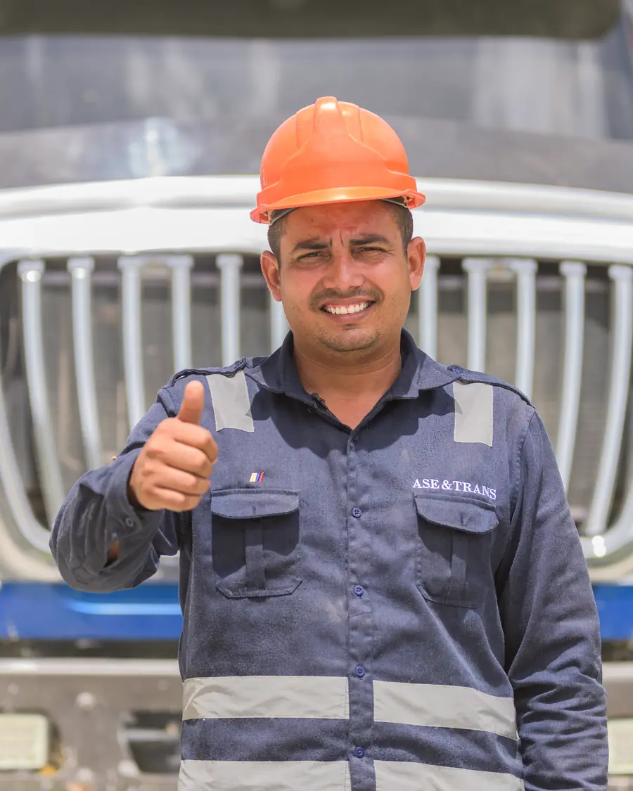 Conductor de ASEYTRANS con casco y uniforme frente a una volqueta dobletroque
